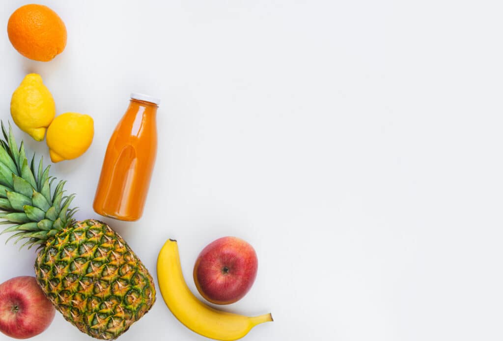 ananas, citron, pomme, orange et une bouteille de jus de fruits